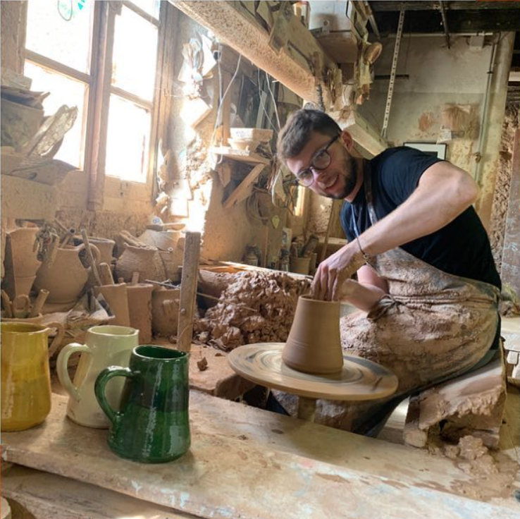 Romain Not, le fils de Jean-PIerre Not devant le tour de la poterie en train de préparer un pichet à eau.